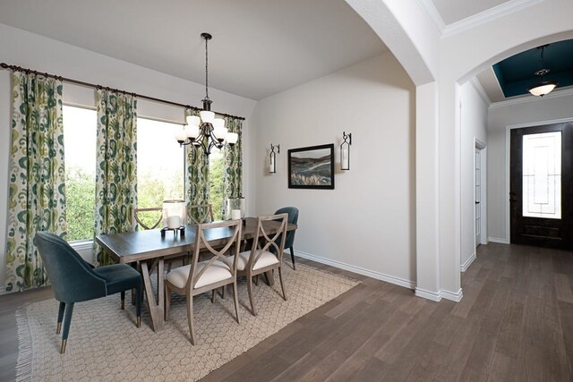 dining room featuring crown molding, baseboards, dark wood-style flooring, and arched walkways