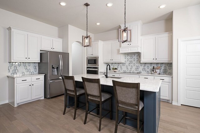 kitchen featuring a sink, light wood finished floors, appliances with stainless steel finishes, and tasteful backsplash