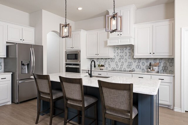 kitchen with a sink, decorative backsplash, stainless steel appliances, and light wood finished floors