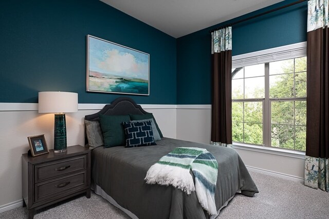 carpeted bedroom featuring baseboards and multiple windows