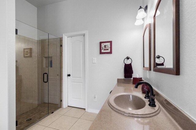 full bath featuring vanity, tile patterned flooring, baseboards, and a stall shower