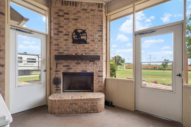 interior space featuring concrete flooring, a healthy amount of sunlight, and an outdoor brick fireplace