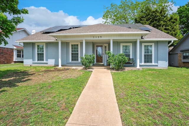 view of front of property with covered porch, solar panels, a front lawn, and brick siding