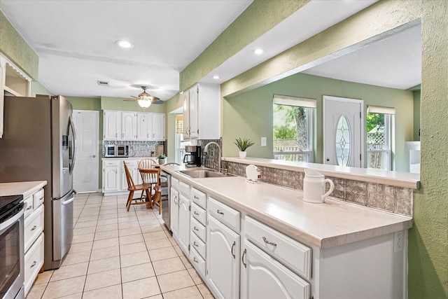 kitchen with tasteful backsplash, white cabinetry, a sink, a peninsula, and light tile patterned flooring