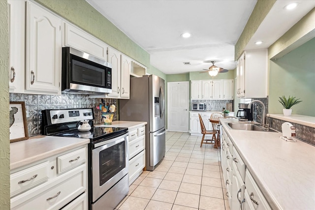 kitchen with a sink, decorative backsplash, white cabinets, and stainless steel appliances