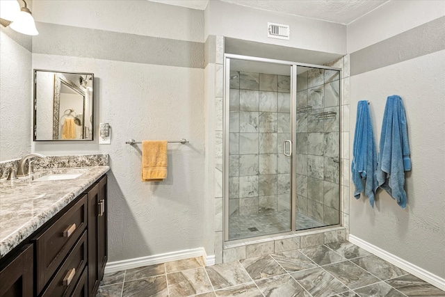 bathroom featuring baseboards, a textured wall, and a shower stall