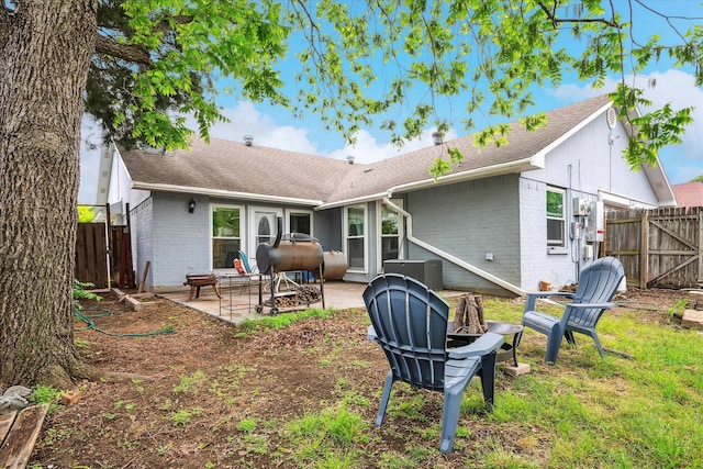 rear view of property with brick siding, a shingled roof, a fenced backyard, and a patio area