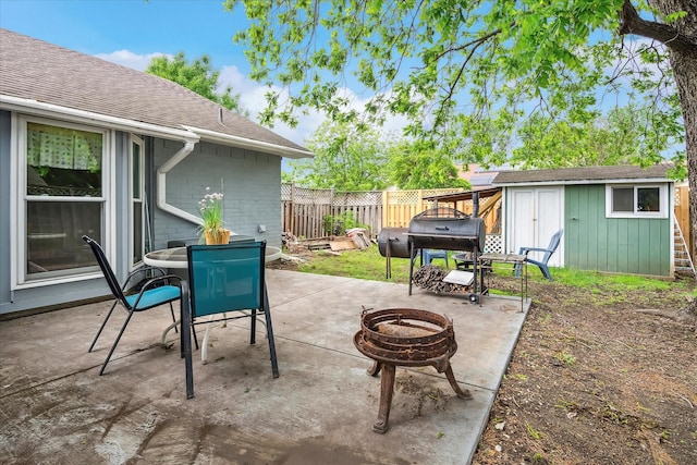 view of patio / terrace featuring an outdoor structure, a fenced backyard, an outdoor fire pit, and a storage unit