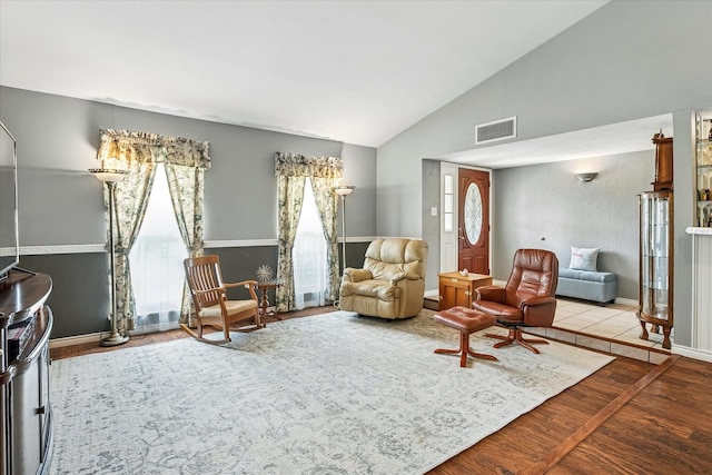 living area with visible vents, wood finished floors, and vaulted ceiling
