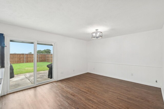 unfurnished room featuring an inviting chandelier, baseboards, and wood finished floors