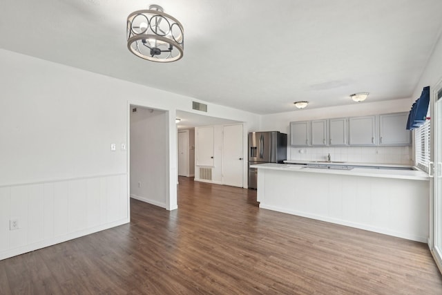 kitchen featuring stainless steel fridge with ice dispenser, light countertops, gray cabinets, visible vents, and dark wood-style floors