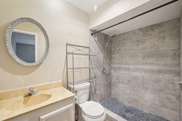 bathroom with vanity, a tile shower, and toilet