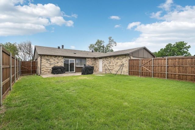 rear view of property featuring a lawn, brick siding, a fenced backyard, and a patio area