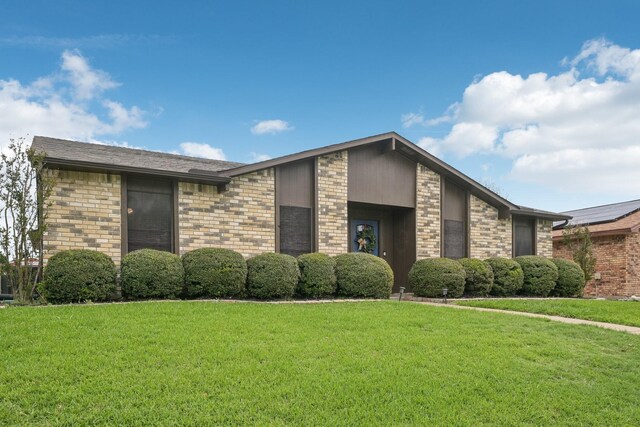 view of front facade with brick siding and a front yard
