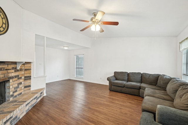 living room featuring a ceiling fan, dark wood-style floors, a brick fireplace, and a wealth of natural light