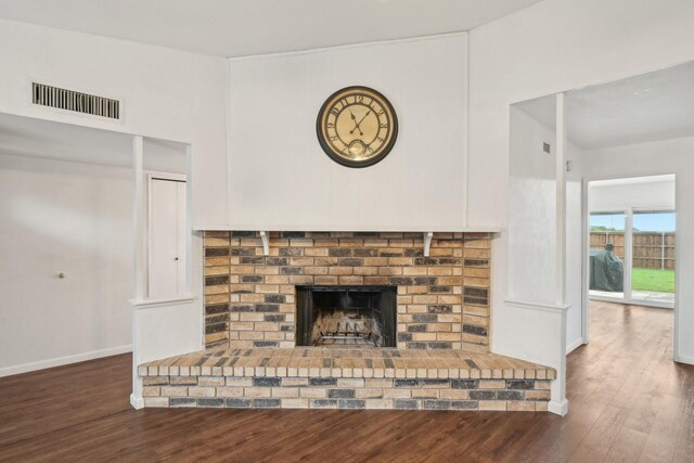 unfurnished living room featuring baseboards, visible vents, wood finished floors, and a fireplace