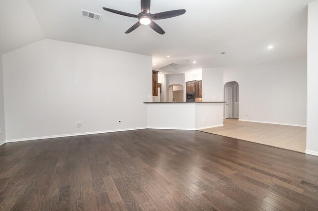 unfurnished living room with visible vents, arched walkways, ceiling fan, and vaulted ceiling