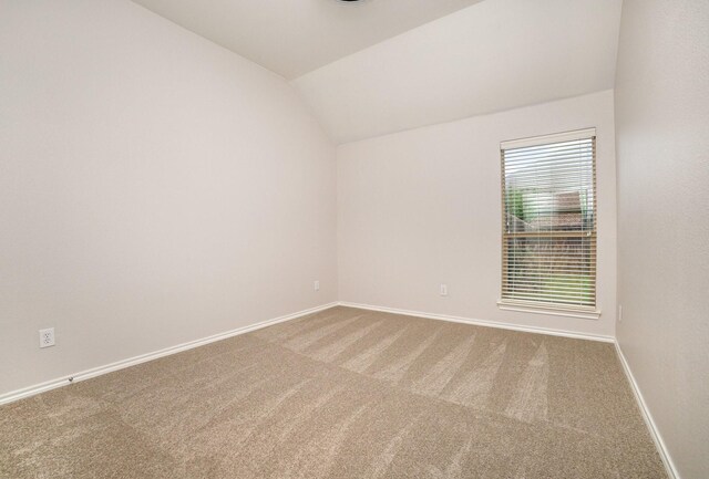 unfurnished room featuring carpet floors, baseboards, and lofted ceiling