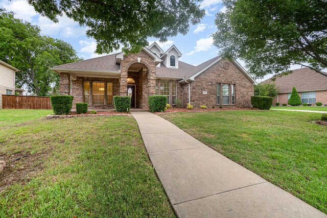 traditional home featuring brick siding, a front lawn, and fence