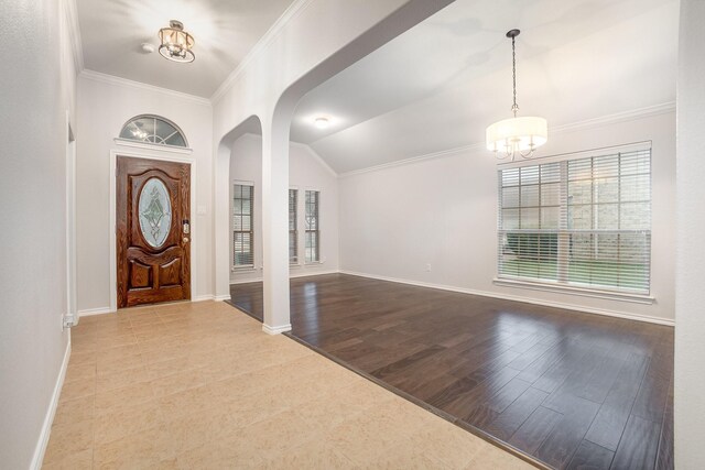 entryway featuring ornamental molding, lofted ceiling, baseboards, arched walkways, and a notable chandelier