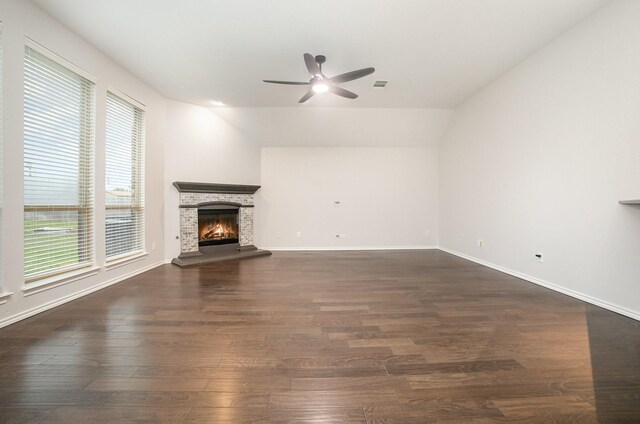 unfurnished living room with ceiling fan, a lit fireplace, visible vents, vaulted ceiling, and dark wood-type flooring