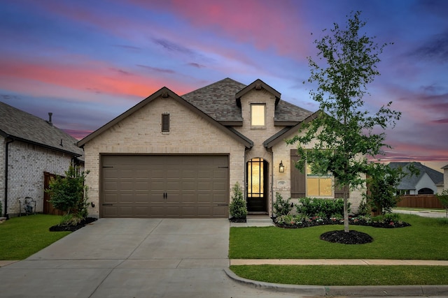 view of front of property featuring a lawn, an attached garage, concrete driveway, and brick siding