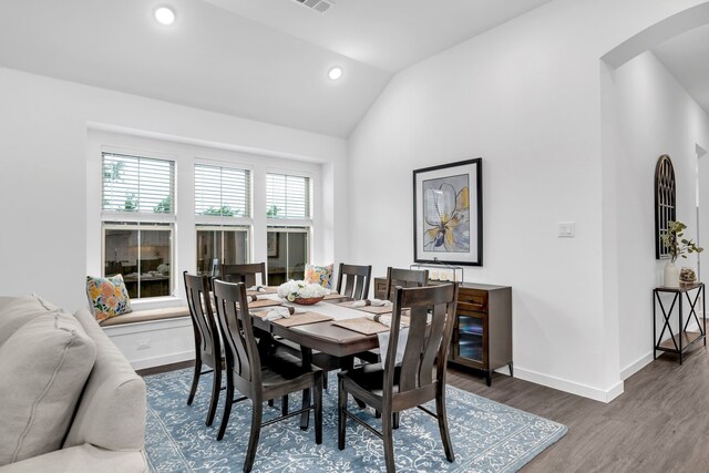 dining space with visible vents, wood finished floors, lofted ceiling, baseboards, and arched walkways
