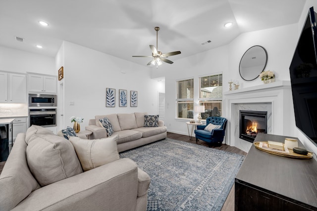 living room featuring a ceiling fan, visible vents, a high end fireplace, recessed lighting, and dark wood-type flooring