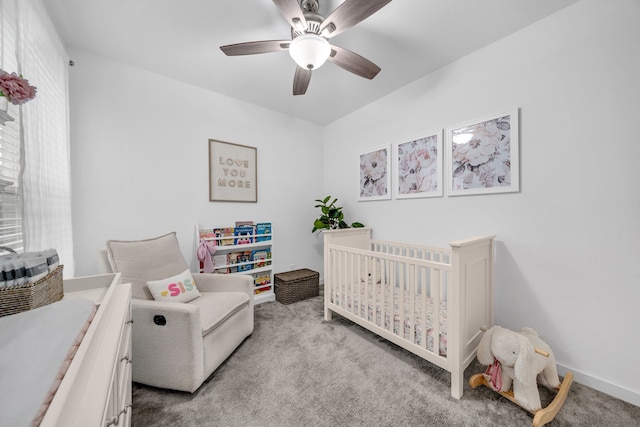 carpeted bedroom featuring a nursery area and ceiling fan