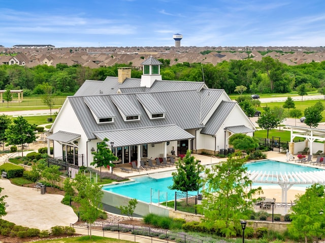 back of house with a patio, a standing seam roof, metal roof, and a fenced in pool