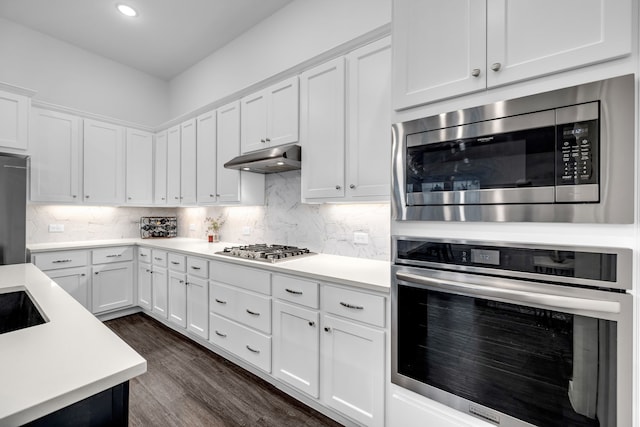 kitchen featuring white cabinets, appliances with stainless steel finishes, light countertops, backsplash, and dark wood-style floors