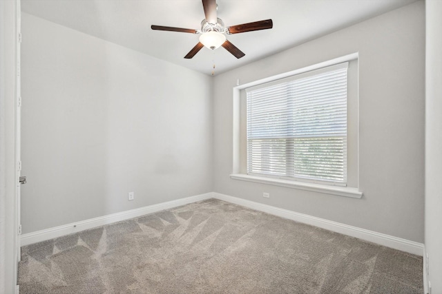 carpeted spare room featuring baseboards and a ceiling fan
