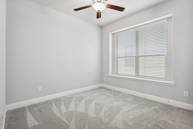 carpeted spare room with baseboards and a ceiling fan