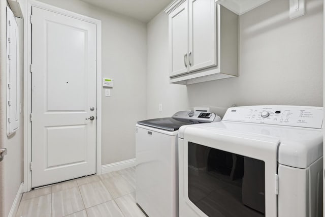 washroom with light tile patterned floors, baseboards, independent washer and dryer, and cabinet space