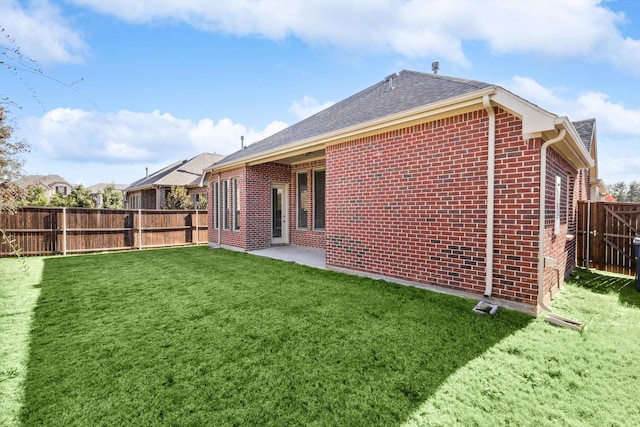 rear view of property featuring a yard, brick siding, a fenced backyard, and roof with shingles