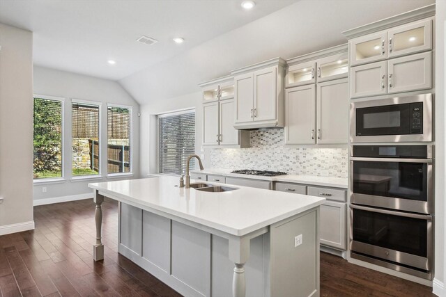 kitchen featuring stainless steel double oven, a sink, built in microwave, lofted ceiling, and dark wood-type flooring