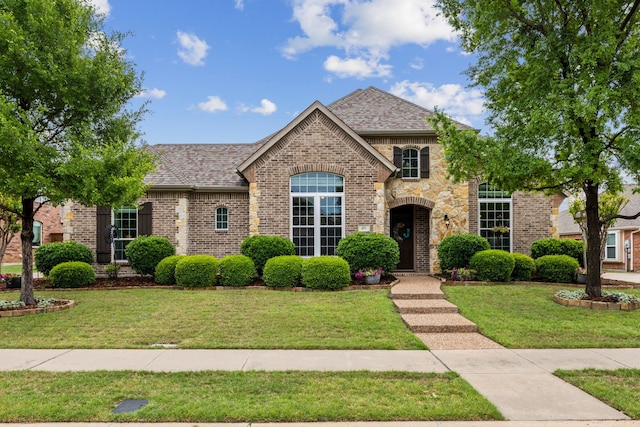 view of front of property with brick siding, a shingled roof, and a front lawn