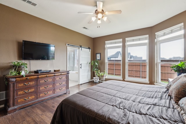 bedroom with dark wood-style flooring, visible vents, a barn door, and multiple windows