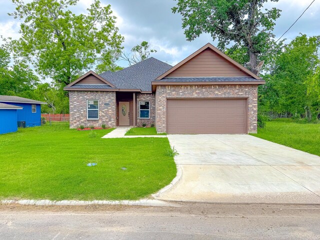 ranch-style home featuring driveway, brick siding, a front lawn, an attached garage, and a shingled roof