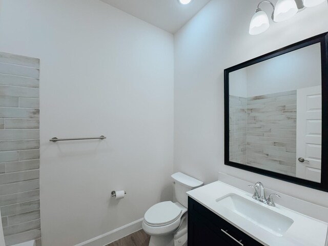 bathroom with toilet, baseboards, wood finished floors, and vanity