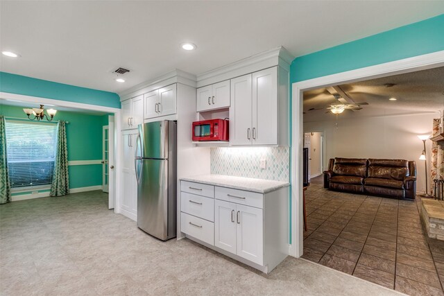 kitchen with visible vents, freestanding refrigerator, white cabinetry, and white microwave