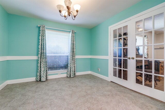 spare room with plenty of natural light, carpet, french doors, and a notable chandelier