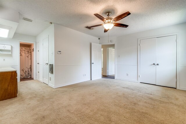 unfurnished bedroom featuring visible vents, a textured ceiling, a closet, and light carpet