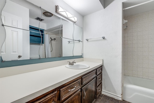 bathroom with baseboards, vanity, tile patterned floors, a textured wall, and tub / shower combination