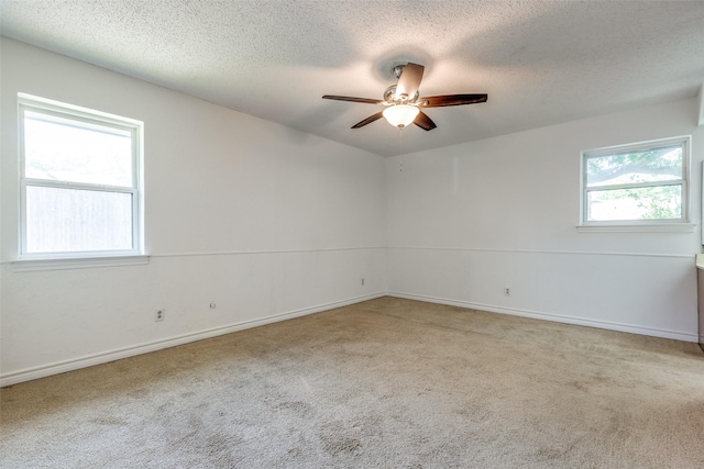 carpeted spare room with a textured ceiling, ceiling fan, and baseboards