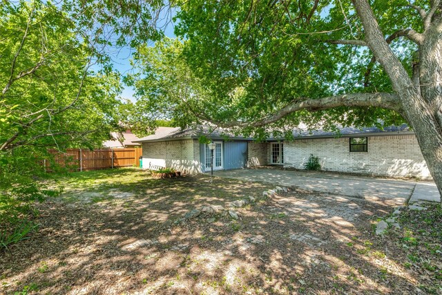 rear view of house with brick siding, fence, and french doors