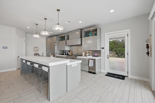 kitchen with light countertops, tasteful backsplash, gray cabinetry, and a kitchen bar