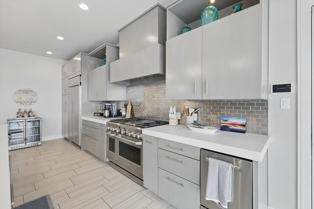 kitchen featuring premium range hood, light countertops, range with two ovens, backsplash, and gray cabinetry