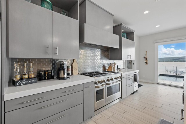 kitchen featuring light countertops, gray cabinets, baseboards, decorative backsplash, and double oven range