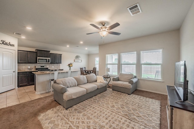 living room featuring visible vents, ceiling fan, and light colored carpet